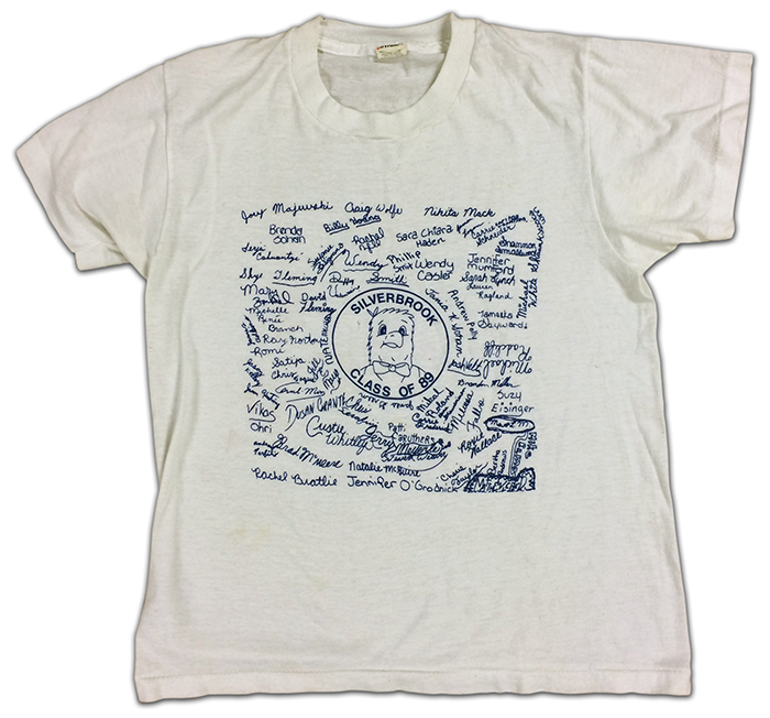 Photograph of a t-shirt given to sixth grade students in 1989. It is a white shirt with artwork in the center showing the Seahawk mascot and the signatures of all the sixth grade students.